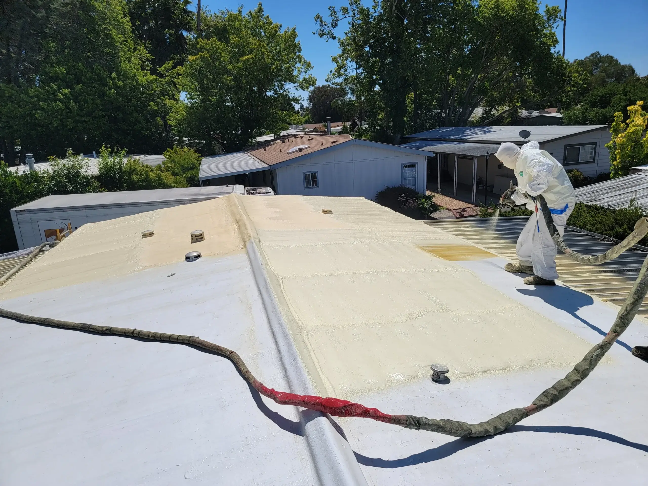 Crew spraying foam roofing on a flat commercial building