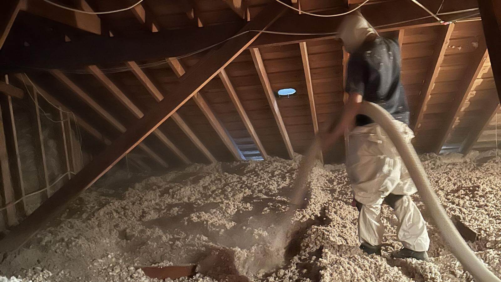 Technician blowing cellulose insulation into an attic